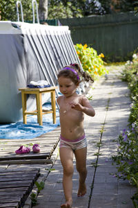 Full length of shirtless girl running at backyard