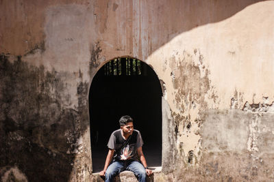 Thoughtful man sitting on arch window