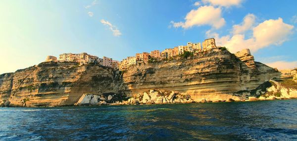 Rock formations by sea against sky