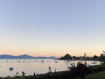 Sailboats in sea at sunset