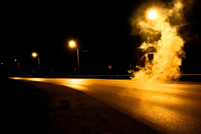 Illuminated road against sky at night