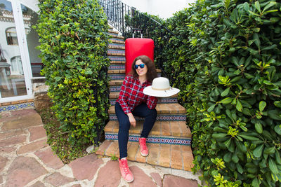 Woman standing by plants against trees