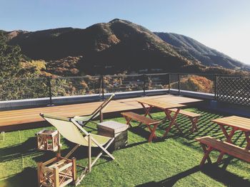 Empty chairs and table against mountains against sky