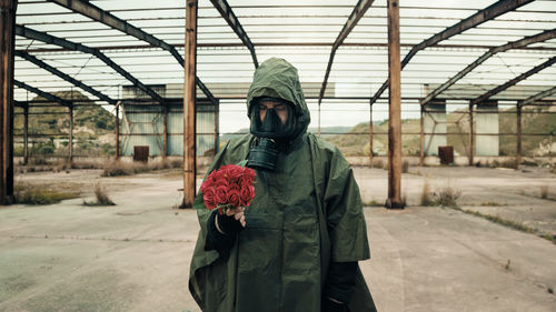 Soldier with bunch of red flowers and gas mask
