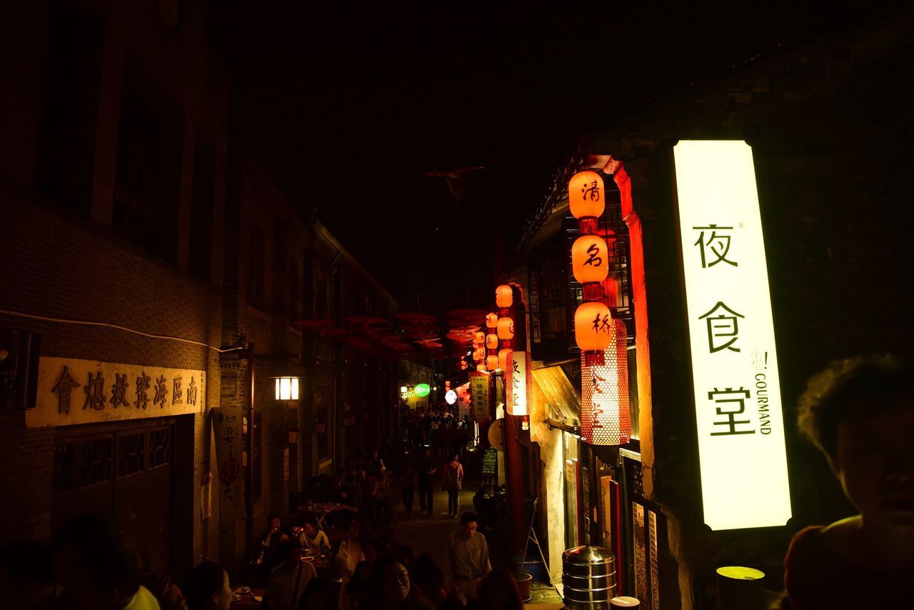 night, illuminated, text, architecture, built structure, building exterior, non-western script, western script, men, large group of people, city, person, street, communication, market, lifestyles, advertisement, store, city life