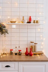Kitchenware and decor on a white shelf in a cozy kitchen with lights. christmas home decoration