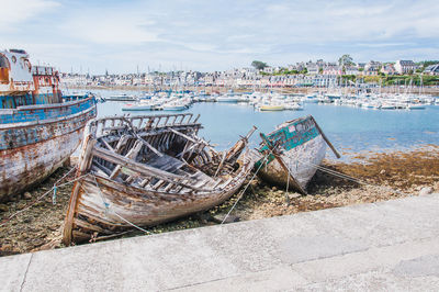 Boats moored on beach against sky in city