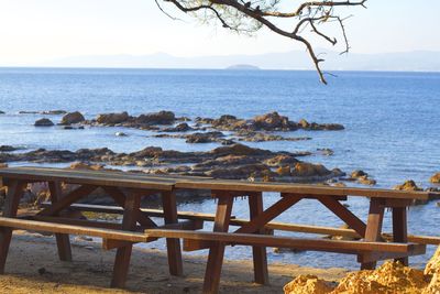 Picnic table on shore against sky