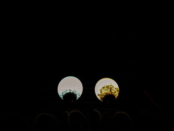 Low angle view of illuminated electric lamp against dark sky