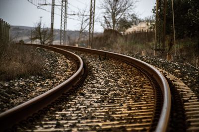 Railway tracks by bare trees against sky