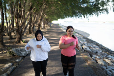 Rear view of mother and daughter standing at beach