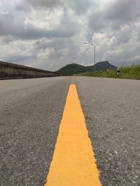 Surface level of road against cloudy sky