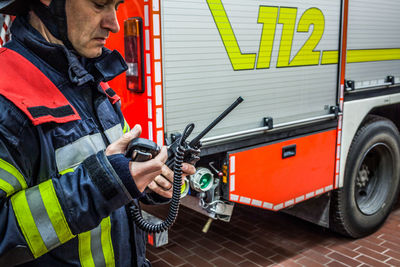 Firefighter using walkie-talkie by fire engine