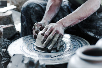 Midsection of person working on pottery wheel