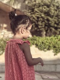 Side view of girl standing against plants