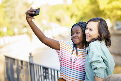 Cheerful women doing selfie while standing outdoors