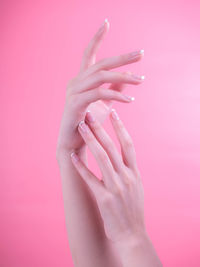 Close-up of woman hand against pink background
