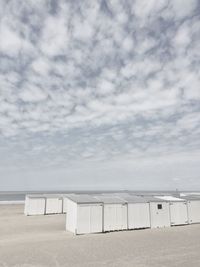 Beach huts on sand against sky