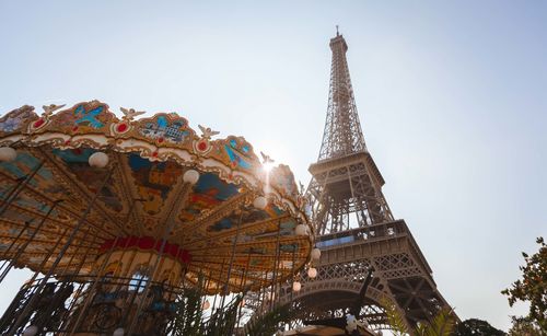 Low angle view of carousel with eiffel tower in background against clear sky