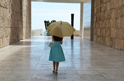 Rear view of woman holding umbrella