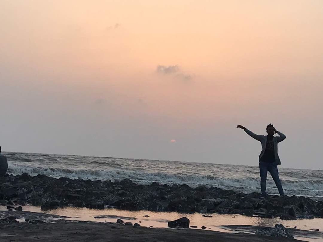 SILHOUETTE MAN STANDING AT BEACH DURING SUNSET