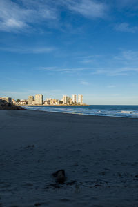 Scenic view of sea by buildings against sky