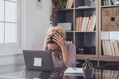 Depressed woman sitting by laptop in office