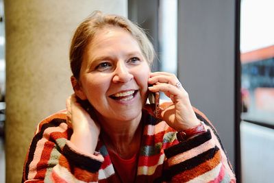 Close-up of smiling mature woman using mobile phone at cafe