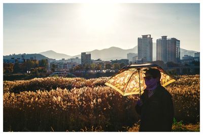 Man standing by cityscape against sky