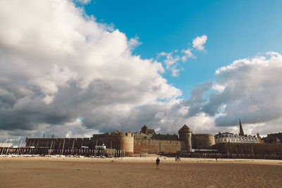 Fort at beach against cloudy sky