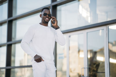 Man using mobile phone while standing on laptop