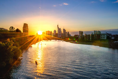 River amidst buildings against sky during sunset