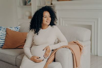 Young woman looking down while sitting on sofa