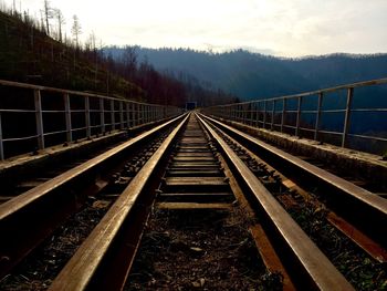 Railroad tracks leading towards mountain against sky