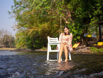 Portrait of a smiling young woman sitting by lake