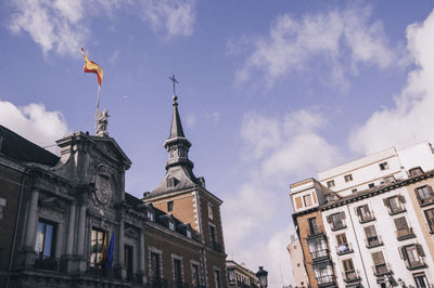 Low angle view of flag on statue in city against sky