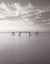 A long exposure monochrome coastal image of the sea including structures and framework in the water.