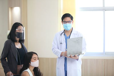 Portrait of doctor with patient wearing mask at hospital