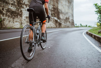 Low section of man riding bicycle on road