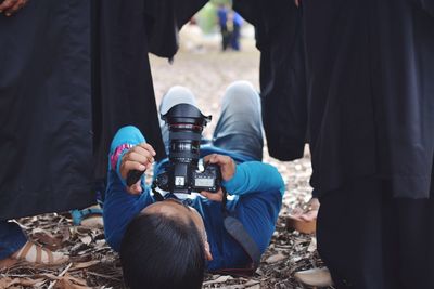 Man lying on ground while photographing through camera