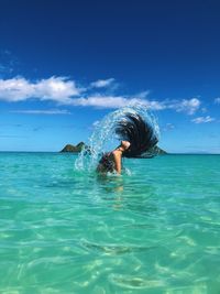 Woman swimming in sea against blue sky