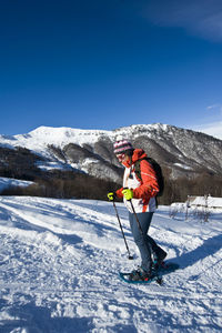 Side view of young man skiing on snowcapped mountain