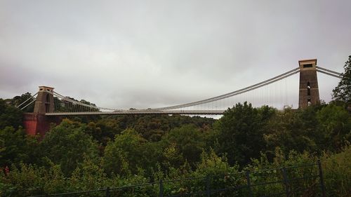 Low angle view of suspension bridge against cloudy sky