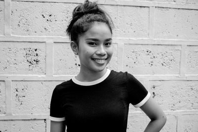 Portrait of smiling girl standing against wall