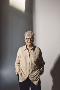 Portrait of senior woman with hands in pockets at studio