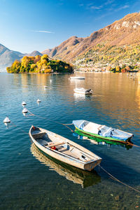 Comacina island, photographed in autumn, with trees, boats and piers around.