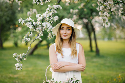 Portrait of a young beautiful woman in the spring flowers of an apple tree