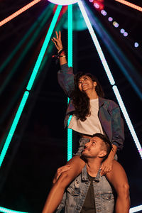 Low angle view of young woman standing in city at night