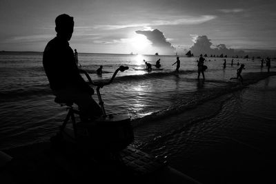 Silhouette people on beach against sky during sunset