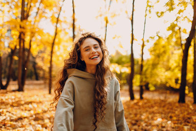 Portrait of young woman standing against trees